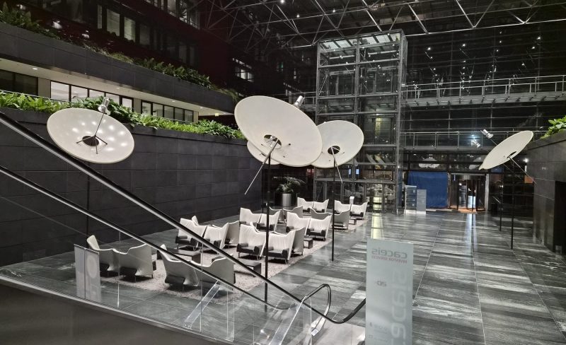 Intérieur moderne du bâtiment de l’Université Populaire Belval à Esch-sur-Alzette, avec un grand atrium vitré, des fauteuils blancs disposés en cercle pour la formation d’improvisation théâtrale, des lampes design suspendues et une atmosphère lumineuse et accueillante.